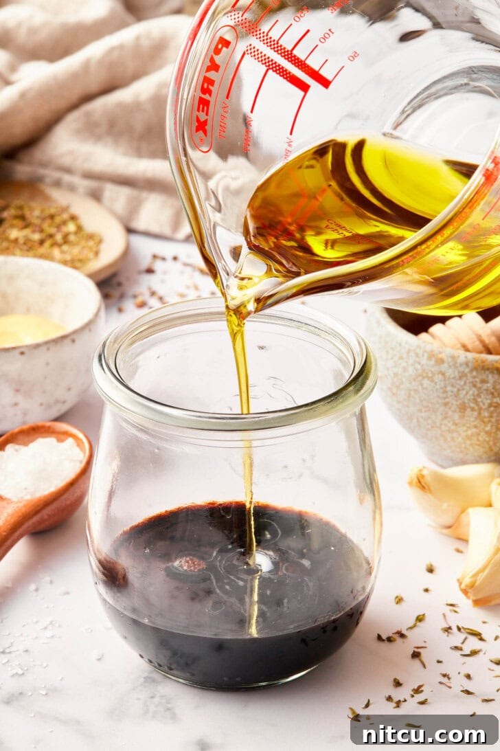 Elevate Your Salad with Homemade Balsamic Vinaigrette 5 balsamic vinaigrette recipe in jar with oil being added