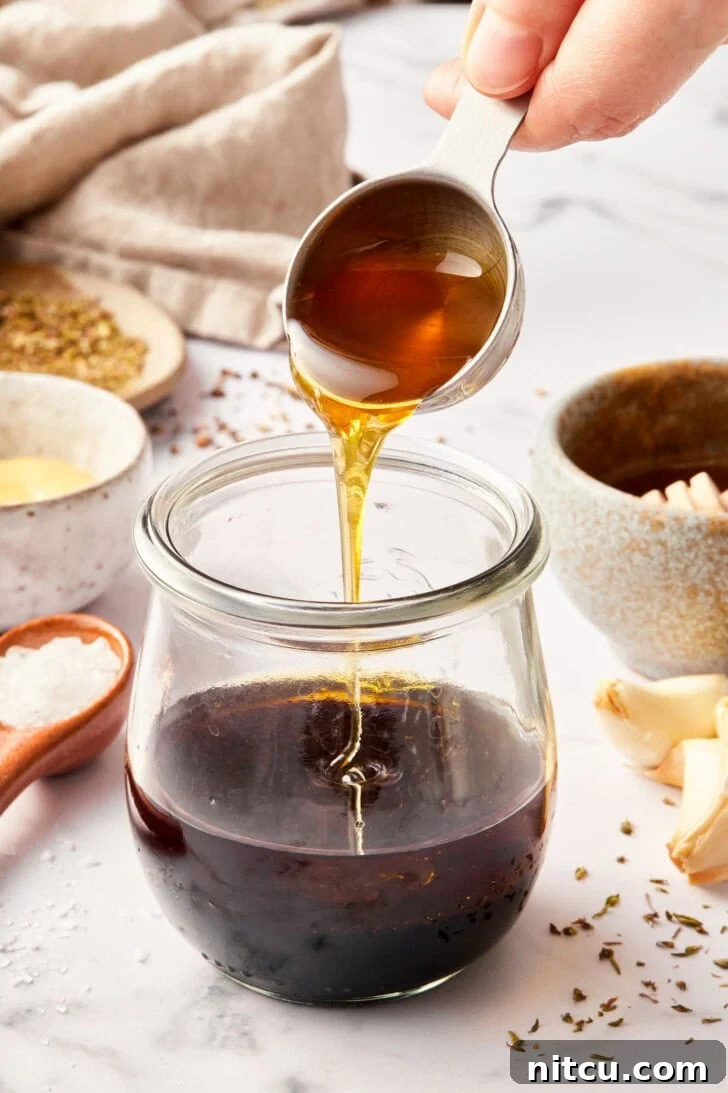 Elevate Your Salad with Homemade Balsamic Vinaigrette 6 balsamic vinaigrette recipe in jar with honey being added