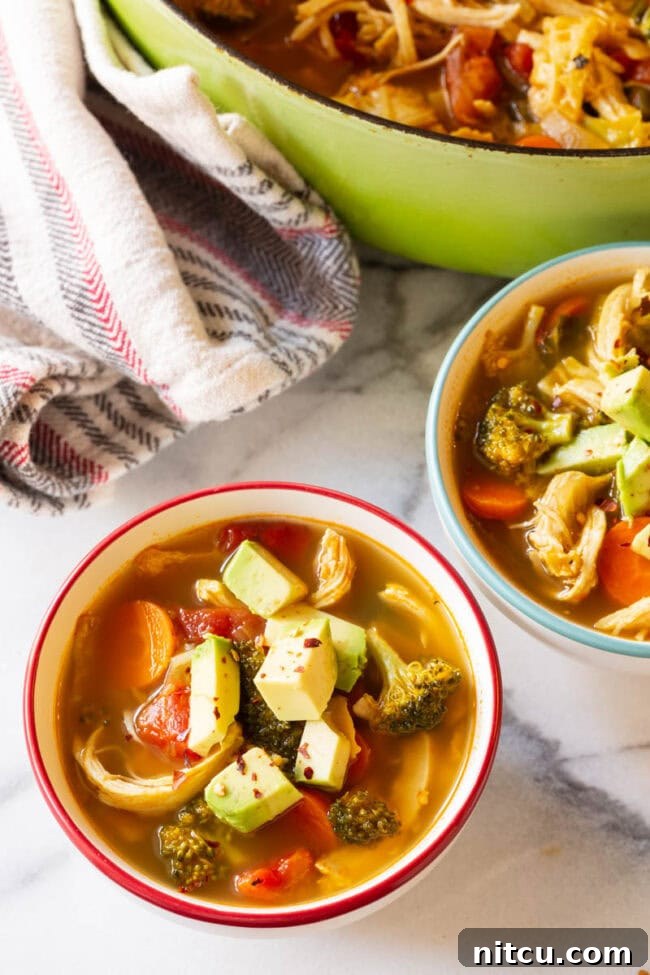 Overhead bowls of low carb chicken soup topped with avocado.