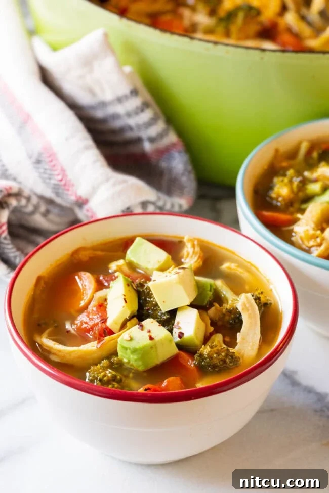Two bowls of detox soup topped with diced avocado.