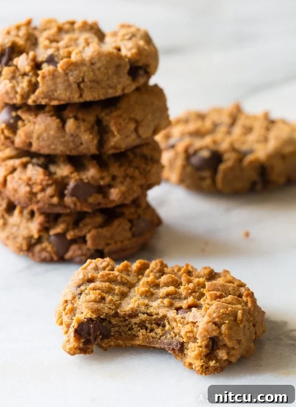 Magic 4-Ingredient Guilt-Free Chocolate Chip Cookies 9 Four delicious cookies in the background, with one perfect cookie in the foreground featuring a bite already taken.