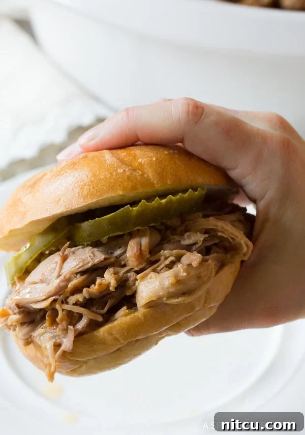 Smoky Perfection: Crockpot Pulled Pork 13 Hand holding a pulled pork sandwich.