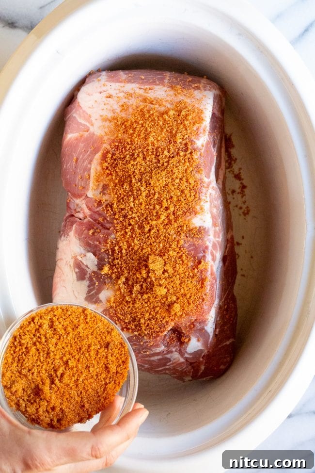 Smoky Perfection: Crockpot Pulled Pork 7 Hand seasoning pork.