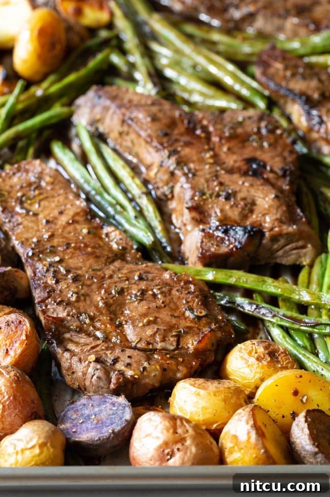 Close-up view of perfectly broiled steak slices with a glistening balsamic glaze, accompanied by roasted mini potatoes and tender green beans.