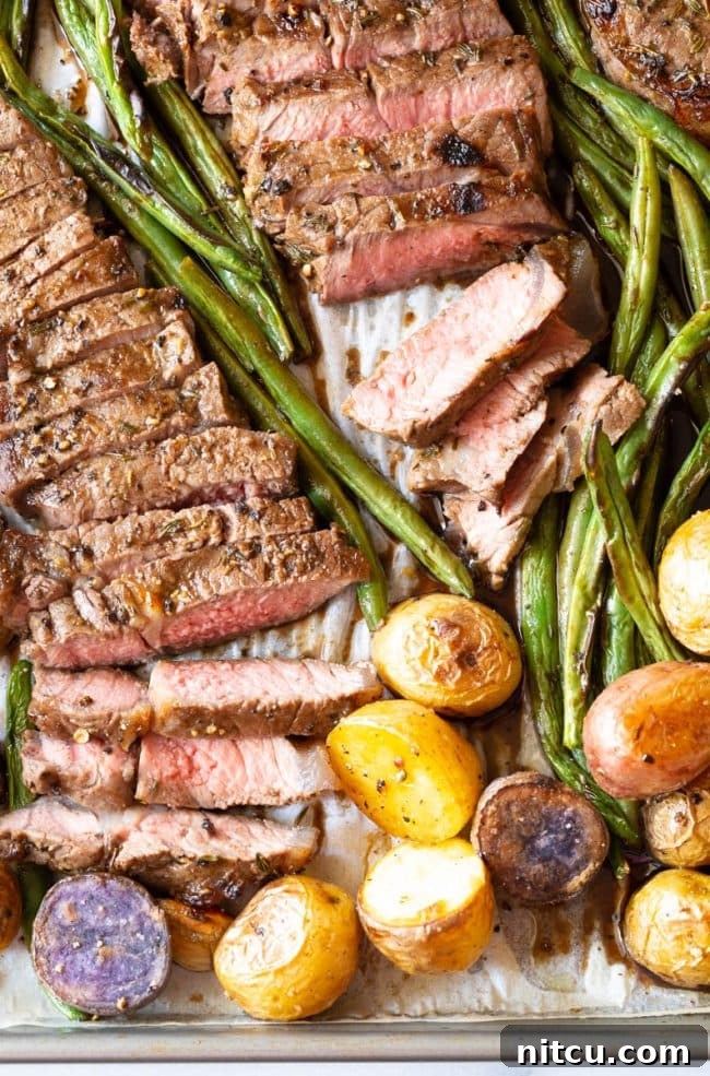 Top view of several slices of medium-rare steak from the sheet pan dinner, showing a perfect pink interior.