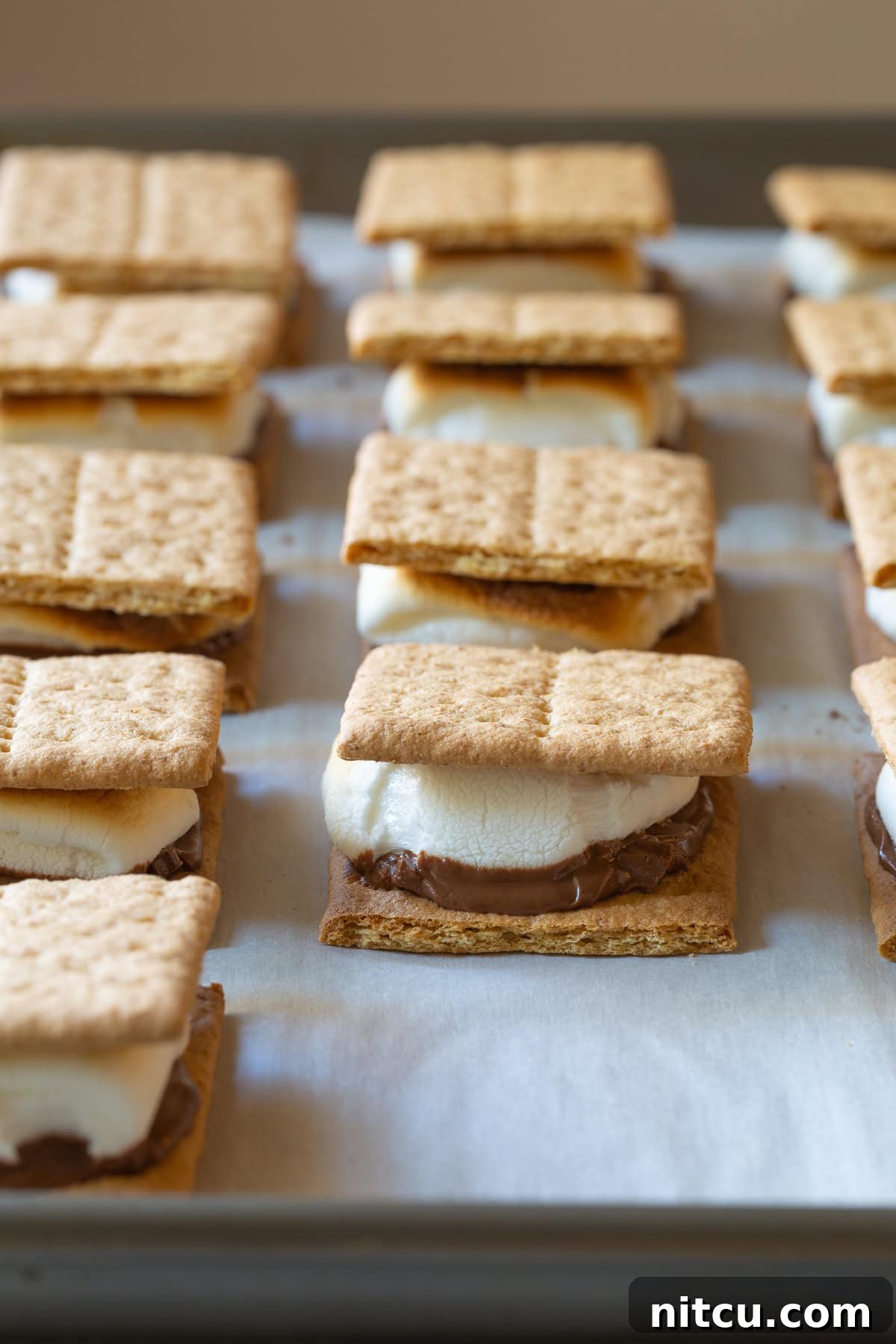 Indoor Smores Delight 4 How To Make Smores In The Oven - Baked s'mores lined up on a baking sheet.