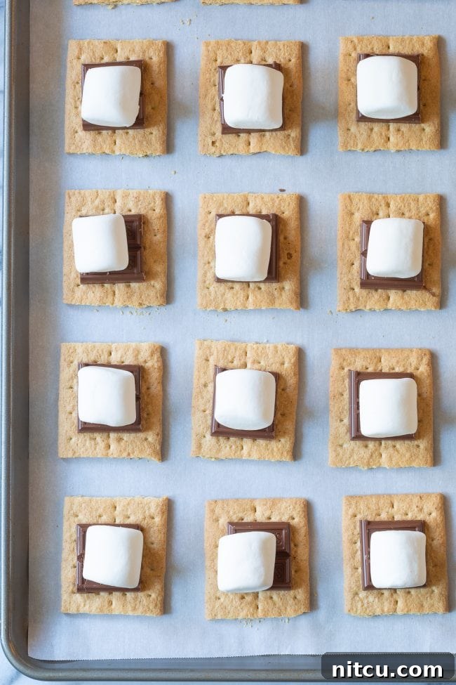 Indoor Smores Delight 5 Overhead shot of graham crackers topped with chocolate and marshmallows before being broiled.