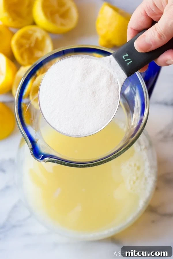 Naturally Sweet Lemonade 7 A hand gently pouring powdered stevia sweetener into a pitcher of lemon juice, ensuring even distribution.