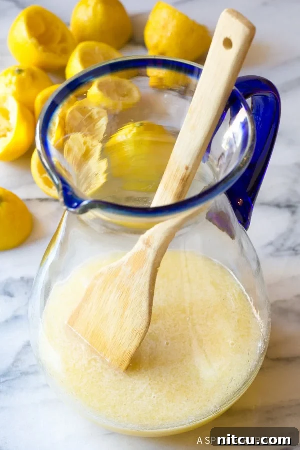 Naturally Sweet Lemonade 8 A wooden spoon actively mixing the lemon juice, stevia, and water together in a pitcher to fully combine the ingredients.