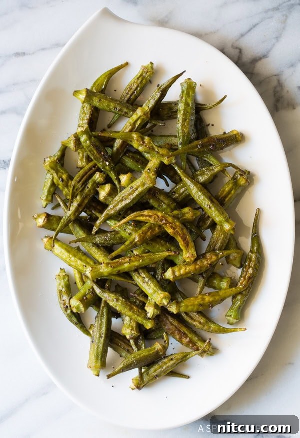 Roasted okra pods with spices on a baking sheet, ready for the oven