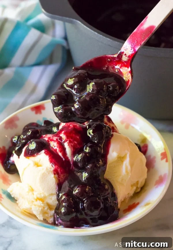 Homemade Blueberry Ice Cream Sauce 5 Spoon drizzling blueberry sauce over a bowl of vanilla ice cream.