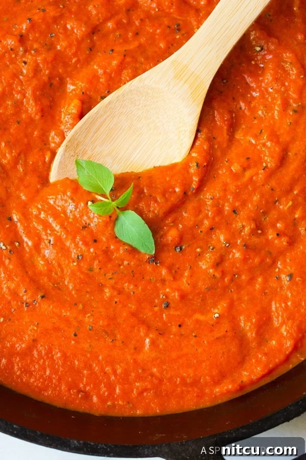 Fire-Roasted Red Pepper Coulis 2 Roasted red pepper sauce with a wooden spoon and sprig of basil.