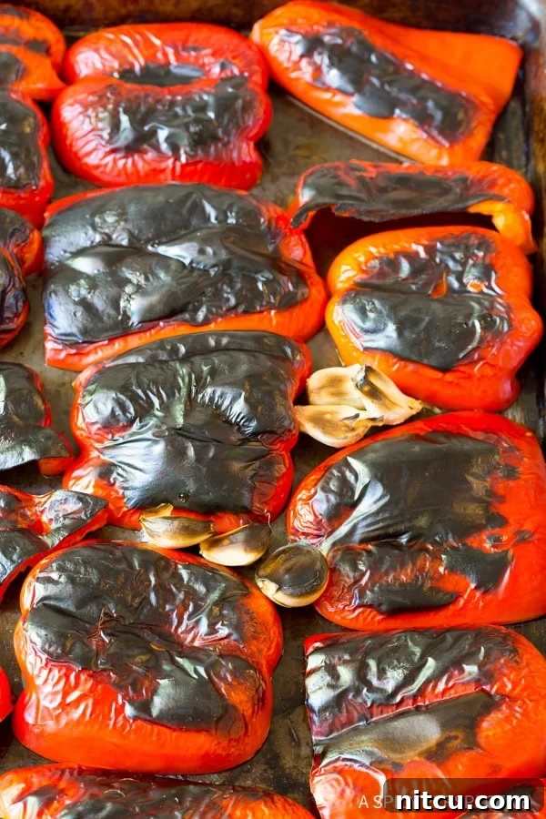 Fire-Roasted Red Pepper Coulis 5 Red bell peppers on a baking sheet after being roasted.