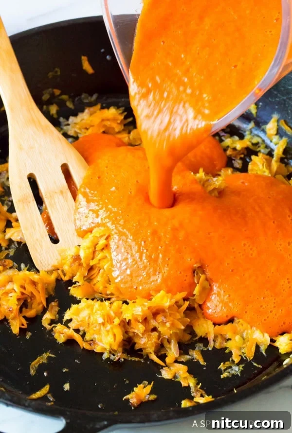 Fire-Roasted Red Pepper Coulis 7 Pouring the blended red peppers into a pan with carrots and onions.