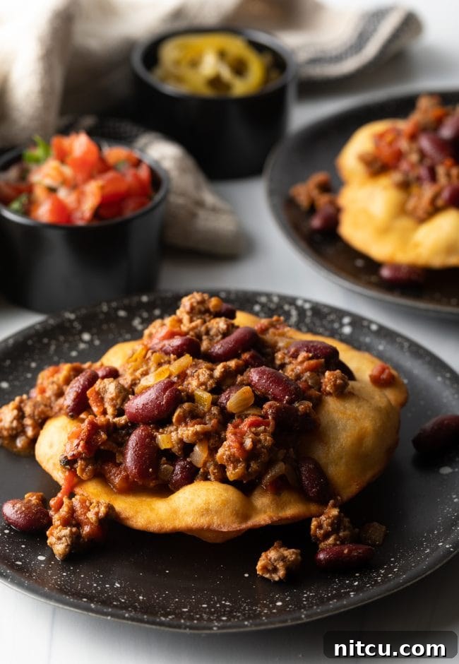 Authentic Navajo Fry Bread 13 Delicious taco meat and red kidney beans artfully arranged on a crispy, golden fry bread base, preparing for further toppings.