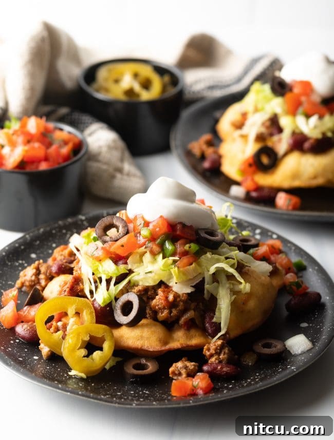 Authentic Navajo Fry Bread 18 A beautifully arranged plate of Indian tacos, each topped with a generous portion of seasoned meat, fresh lettuce, and other colorful garnishes, ready to be enjoyed.
