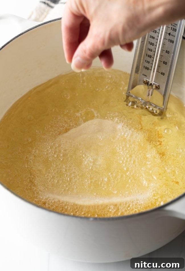 Authentic Navajo Fry Bread 9 A piece of Navajo fry bread actively frying in hot oil within a large Dutch oven, showing the bubbling oil and the dough beginning to puff.