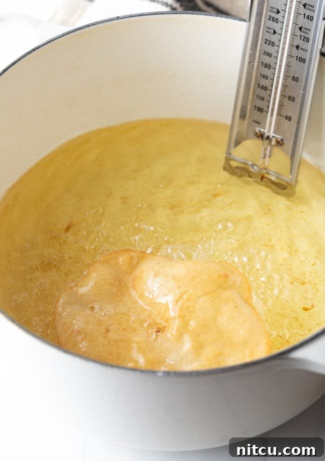 Authentic Navajo Fry Bread 10 Tongs carefully flipping a piece of fry bread in the hot oil, revealing its golden-brown underside as it continues to cook evenly.