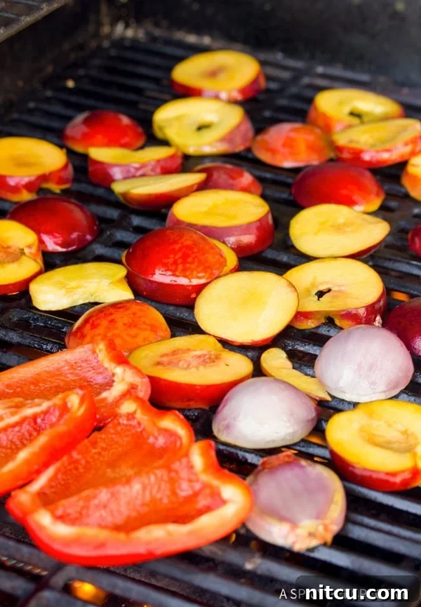 Closeup of peaches, shallots, and red bell peppers being expertly grilled, showcasing the charring process.