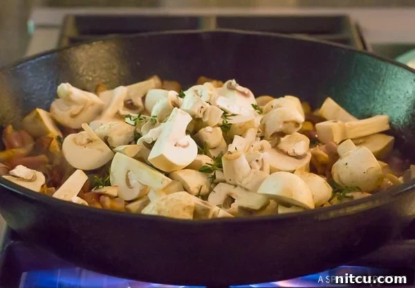Authentic Croatian Chicken Dinner 6 Earthy button mushrooms being sautéed in a hot skillet, beginning to soften and release their flavors.