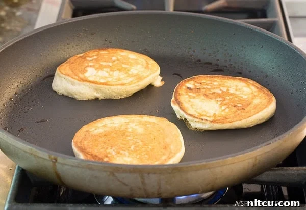 Pillowy Cloud Bread Pancakes 6 Golden brown pancakes in a skillet.