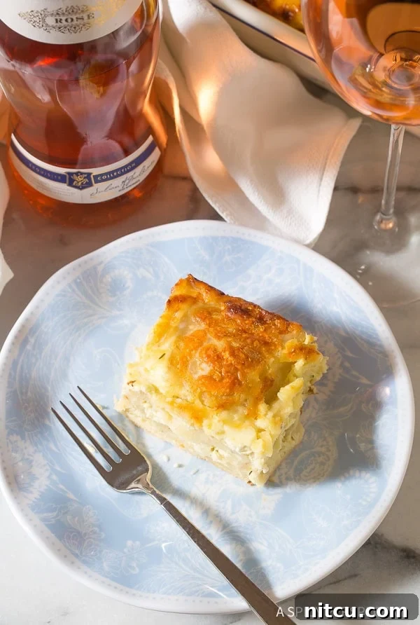 Slice of Croatian cheese strukli served on a plate with a glass of wine on the side. 