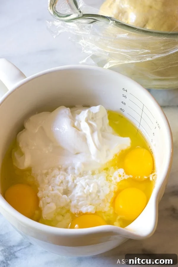 Cottage cheese, sour cream, and eggs in a mixing bowl. 