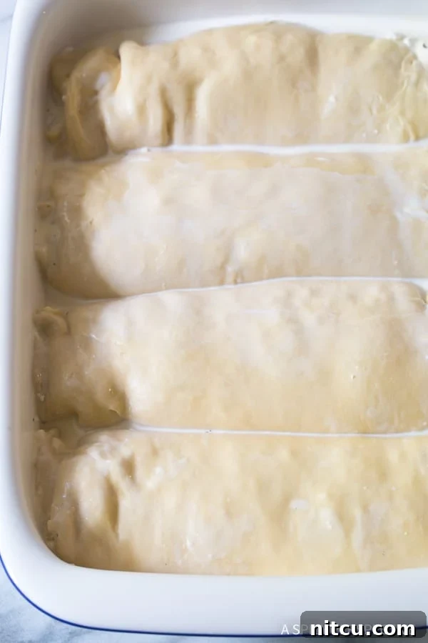 Logs of dough laid next to each other in a baking dish. 