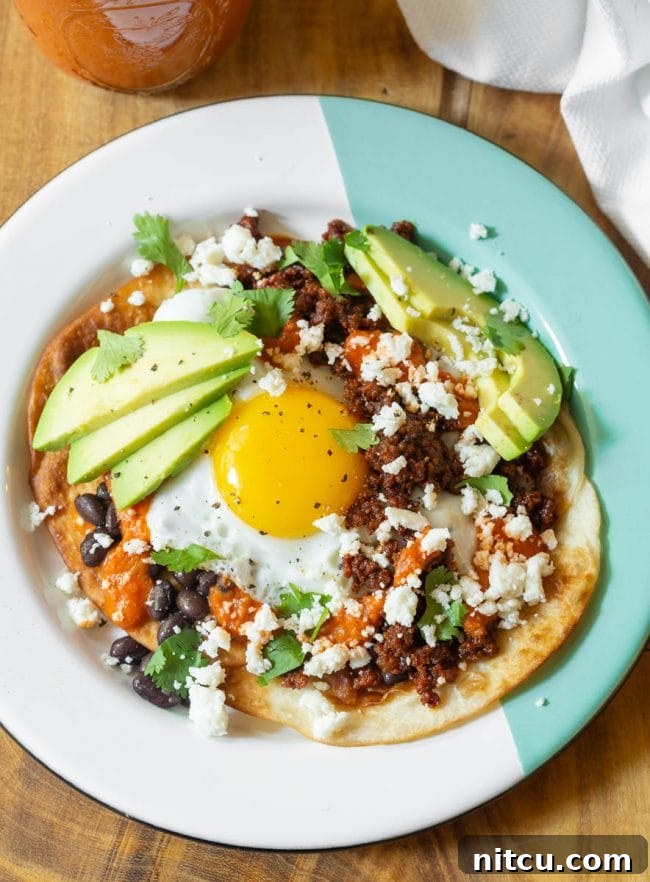 Hearty Ranch Eggs with Zesty Salsa 12 Overhead shot of Huevos Rancheros with sliced avocado and fresh cilantro.