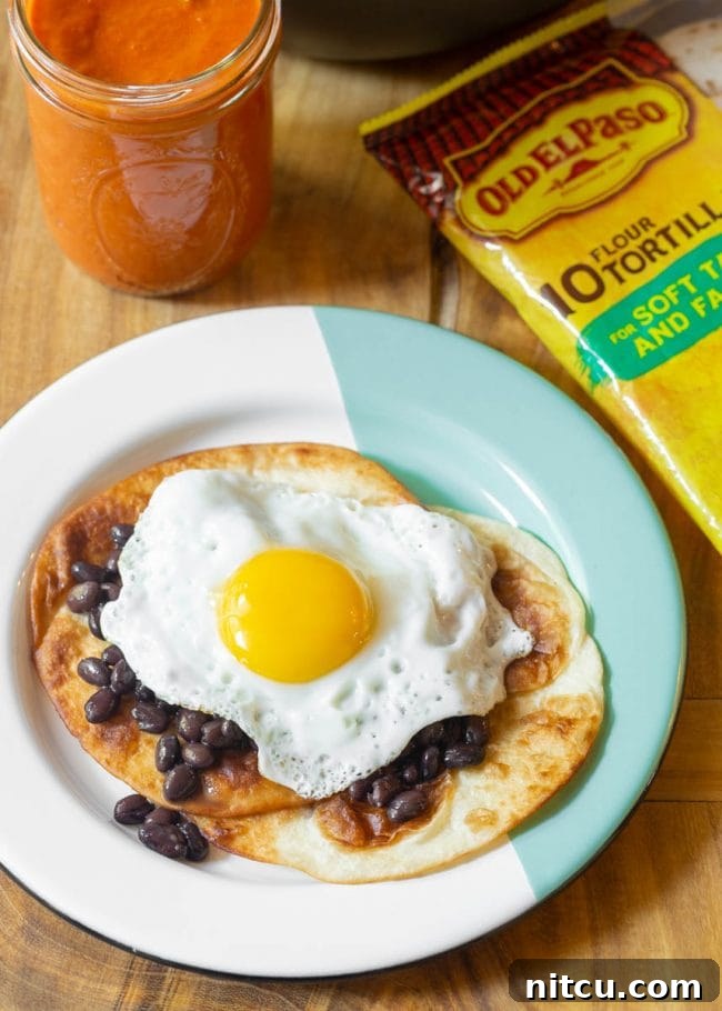 Hearty Ranch Eggs with Zesty Salsa 10 Stacked fried tortillas on a plate with fried egg and beans, ready for sauce.