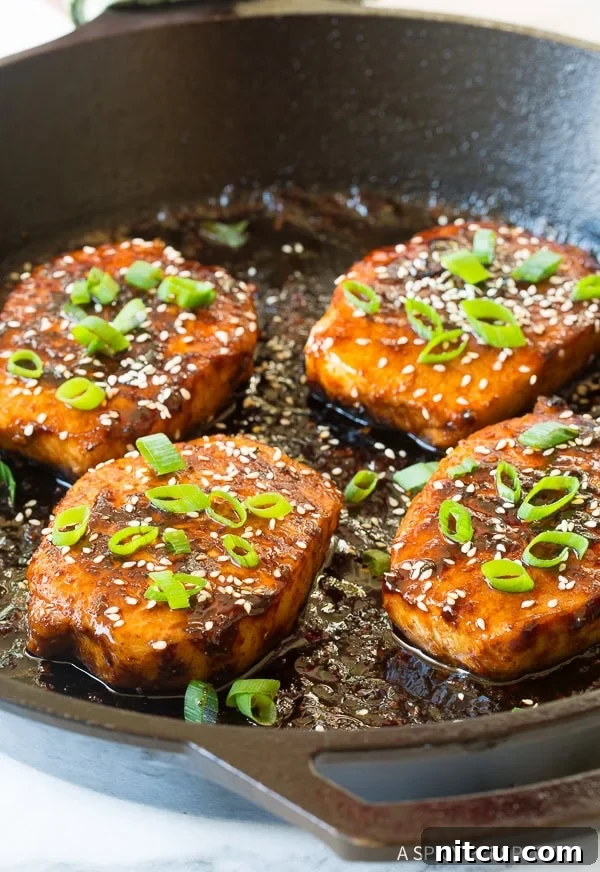 Korean Pork Chops Recipe artfully arranged in a skillet with a sprinkle of sesame seeds and green onions.