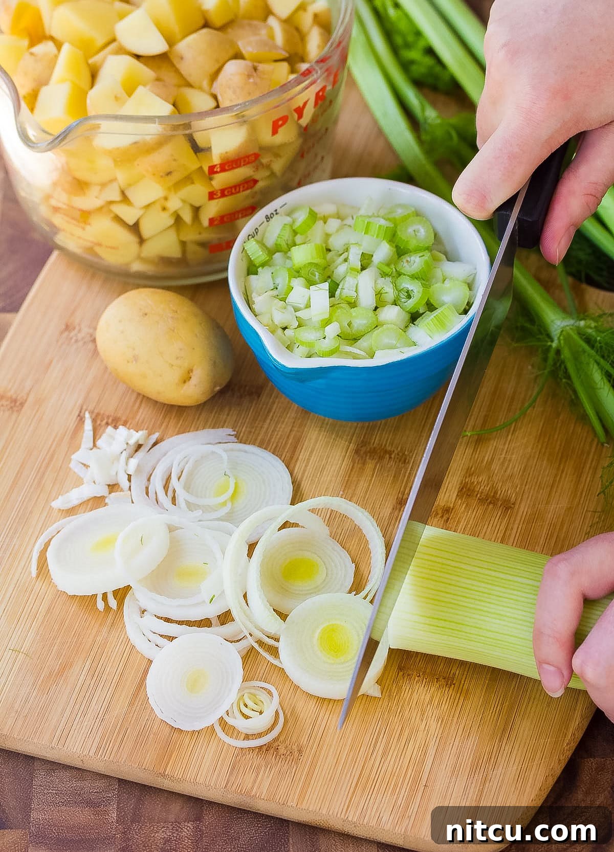 ingredients for New England clam chowder laid out on a cutting board, emphasizing fresh produce