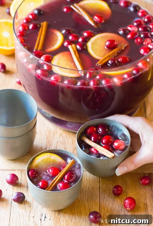 Festive Wine Medley 4 A hand reaching for a glass of the festive Holiday Wine Punch, with the elegant punch bowl brimming in the background, signaling a joyful celebration.