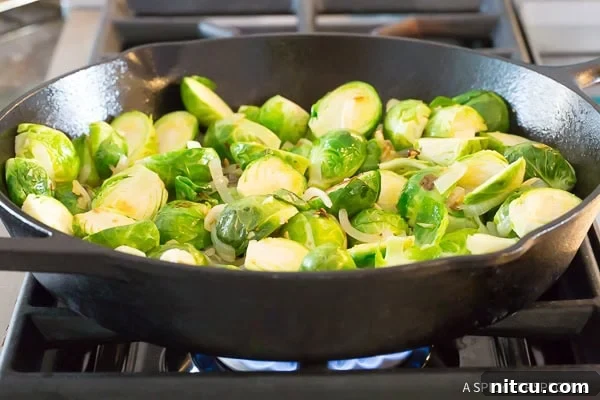 Halved fresh brussels sprouts in a cast iron skillet, ready for searing.