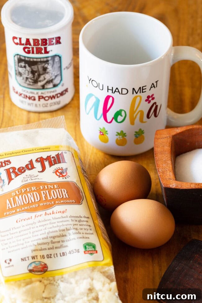 Effortless Keto Mug Bread 3 A white mug, container of baking powder, bag of almond flour, two eggs, and a wood bowl of salt.