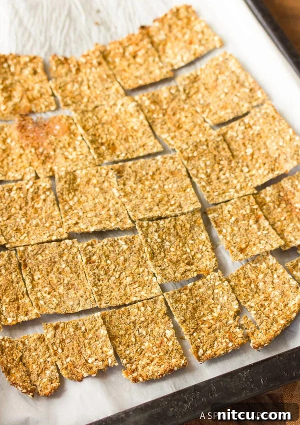 Crispy Keto Cauliflower Bites 2 A parchment paper lined baking sheet covered with perfectly baked squares of golden grain-free cauliflower crackers.