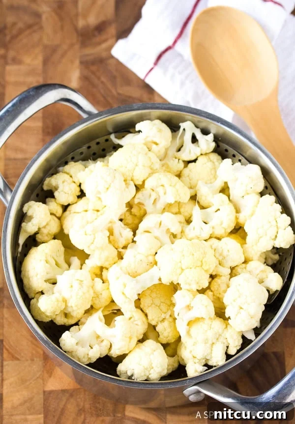 Crispy Keto Cauliflower Bites 4 Freshly cut cauliflower florets resting in a steaming basket, ready for preparation to become delicious low carb crackers.