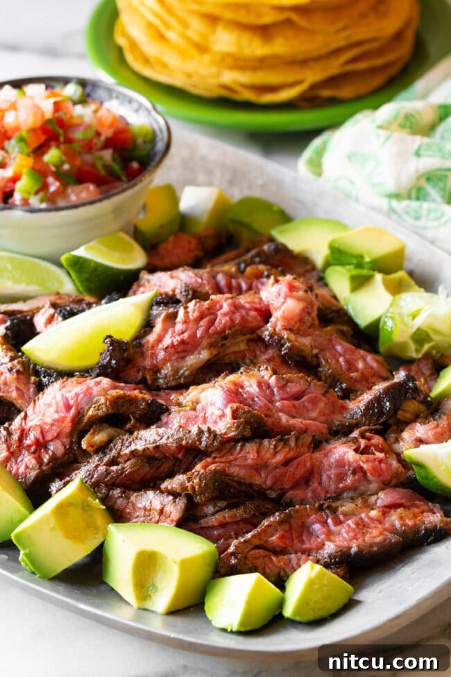 The Secret to Tender Carne Asada 11 Cooked and thinly sliced Carne Asada steak arranged on a platter, ready for serving.
