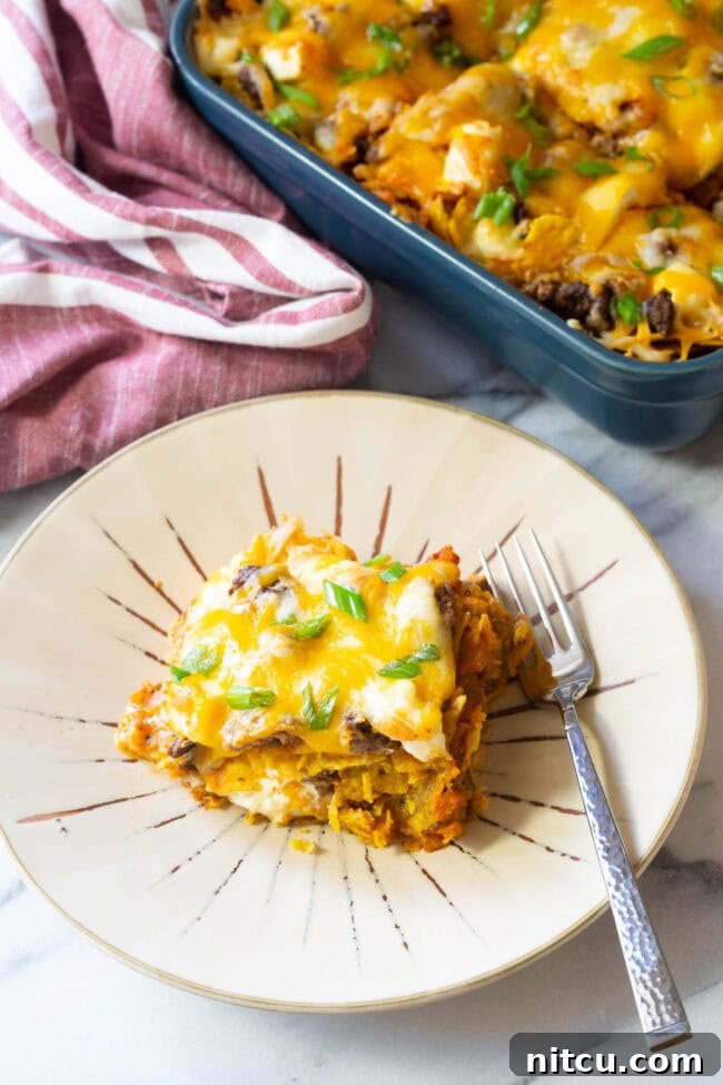 A slice of Dorito lasagna on a plate, ready to be enjoyed with a fork.
