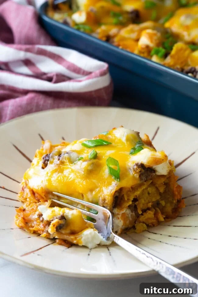 A delectable piece of Doritos casserole on a plate, with a fork having just taken a bite, highlighting its inviting texture.