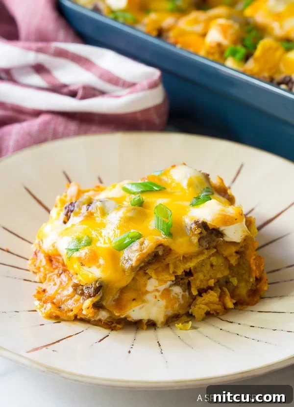 A close-up view of a plated slice of Dorito casserole, revealing the distinct layers and gooey cheese.