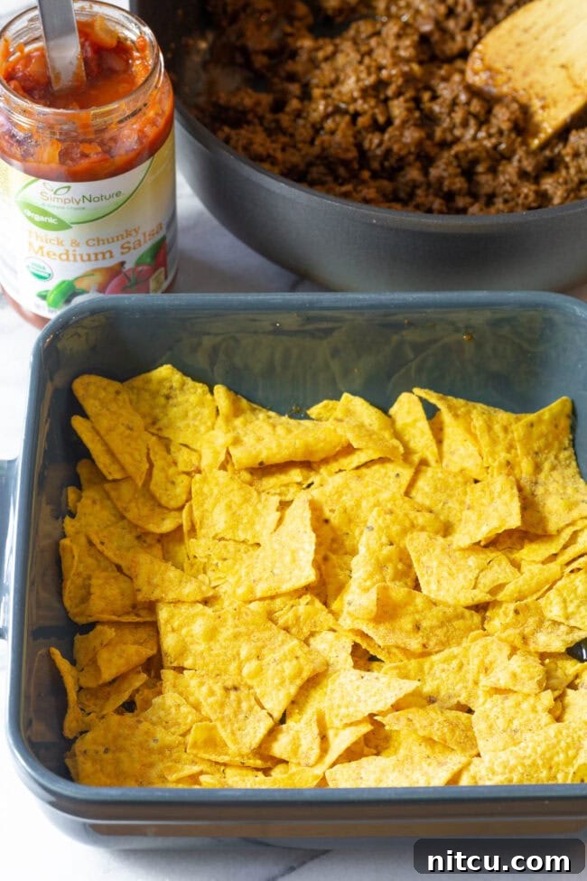 Crushed Cool Ranch Doritos forming the first layer in a baking tray.