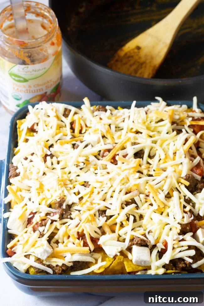 The baking dish with the Dorito mixture fully assembled, topped off with a final generous layer of shredded cheese.
