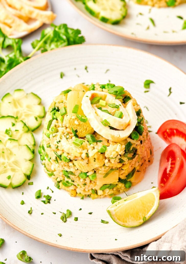 The Ultimate Thai Fried Rice 2 A perfectly plated mound of Thai fried rice, garnished with fresh tomatoes, cucumbers, and lime wedges, ready to be enjoyed.