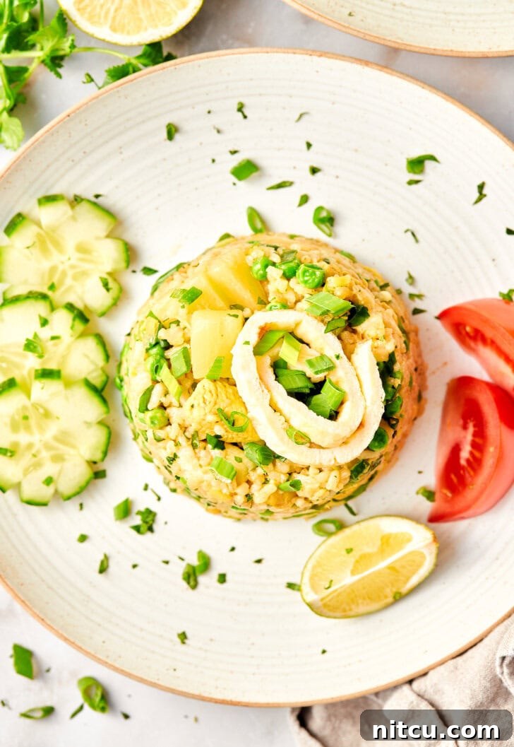 The Ultimate Thai Fried Rice 5 A serving of perfect Thai Fried Rice on a plate, surrounded by fresh cucumbers, tomatoes, lime wedges, and chopsticks, ready for a delicious meal.