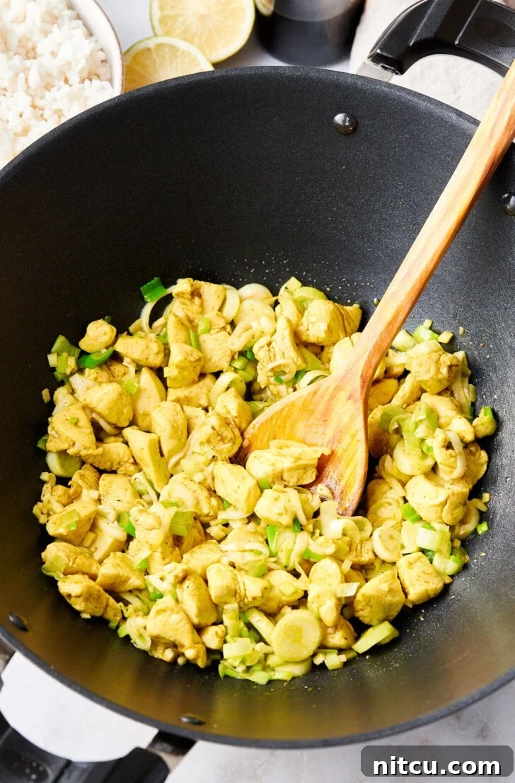 The Ultimate Thai Fried Rice 7 Sautéed chicken and vegetables sizzling in a large skillet, building the flavor base for the fried rice.