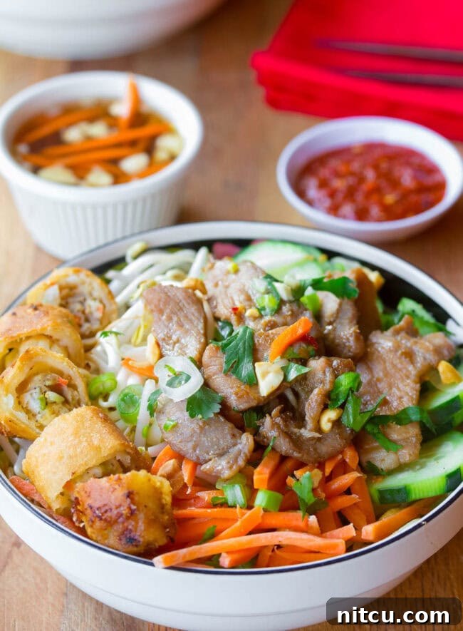 Bun Cha in a bowl with sauces in the background. 