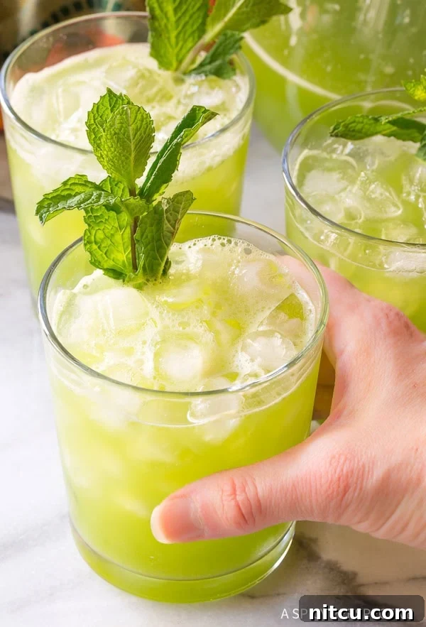 Crisp Cucumber Cooler 3 Three glasses of cucumber agua fresca with a hand grabbing one glass.