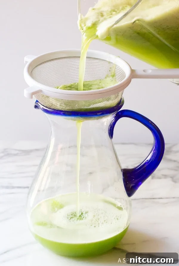 Crisp Cucumber Cooler 7 Hand pouring the agua fresca from the blender into a pitcher with a strainer on top.