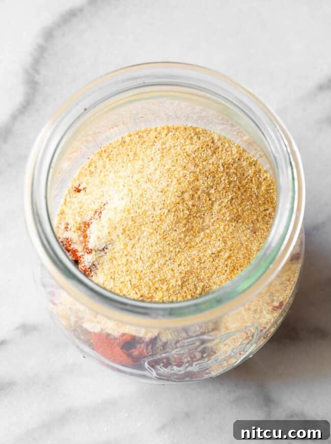 An inviting overhead view of a perfectly filled glass jar of homemade blackened seasoning, showcasing its rich color and texture.